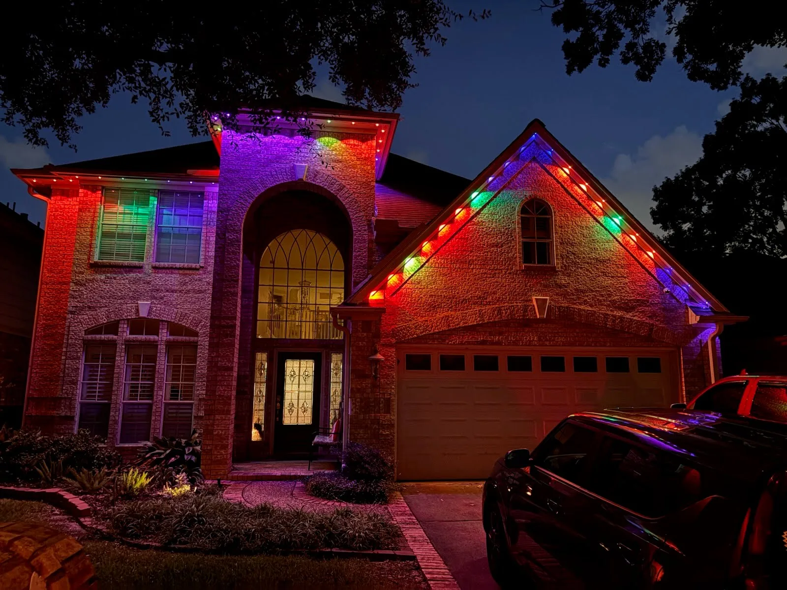 Real BrightSky install — Houston brick home with permanent roofline lighting in full multicolor at night
